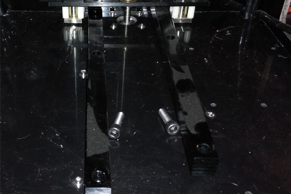 Barra de sujección de la cama caliente desmontada con sus tornillos